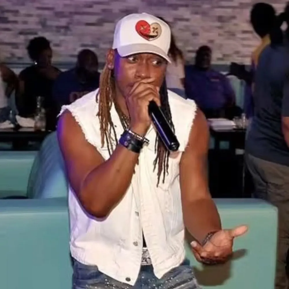 Prep Cashmere performing on stage in a white sleeveless denim vest